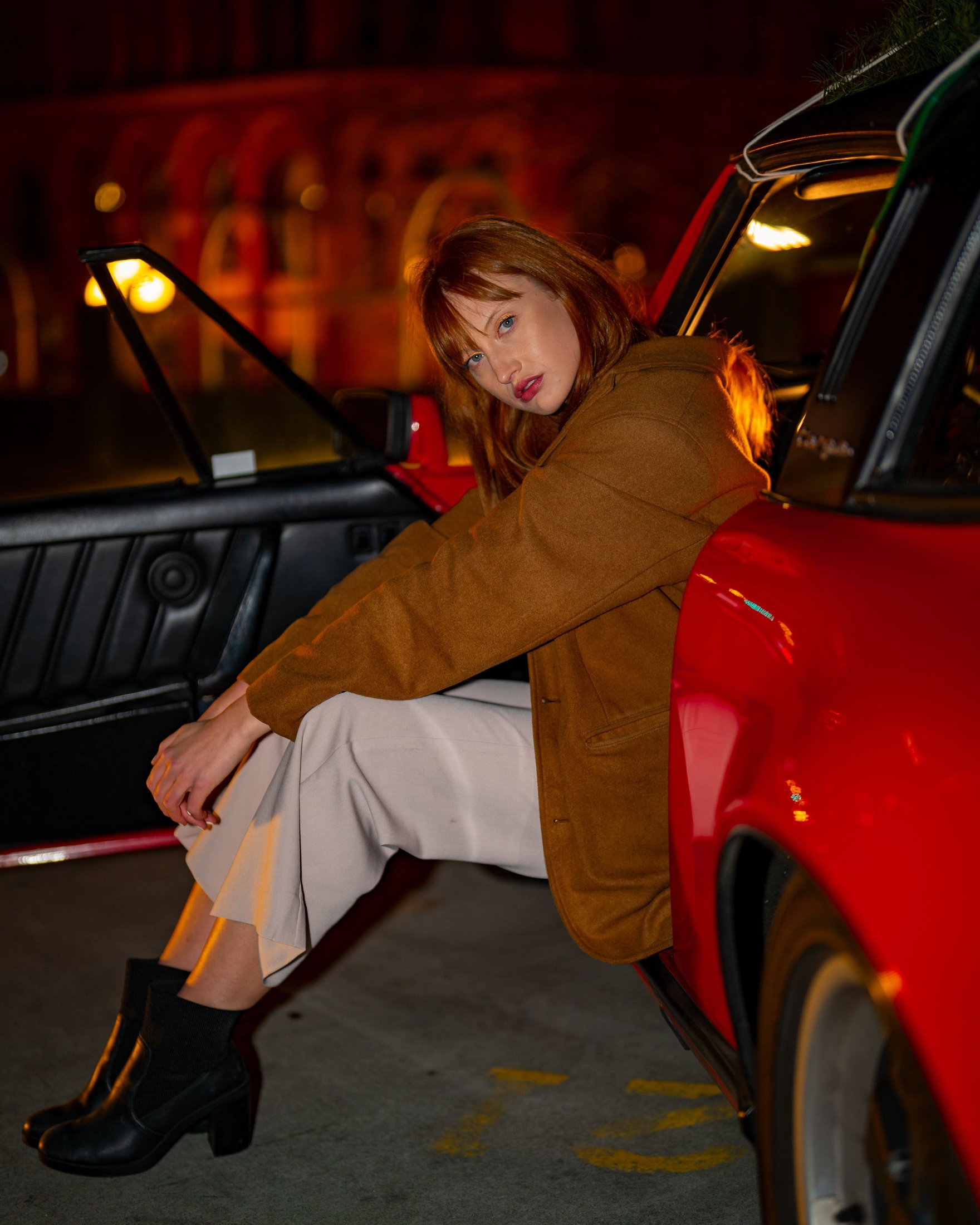 Fashion portrait beside a red car at night