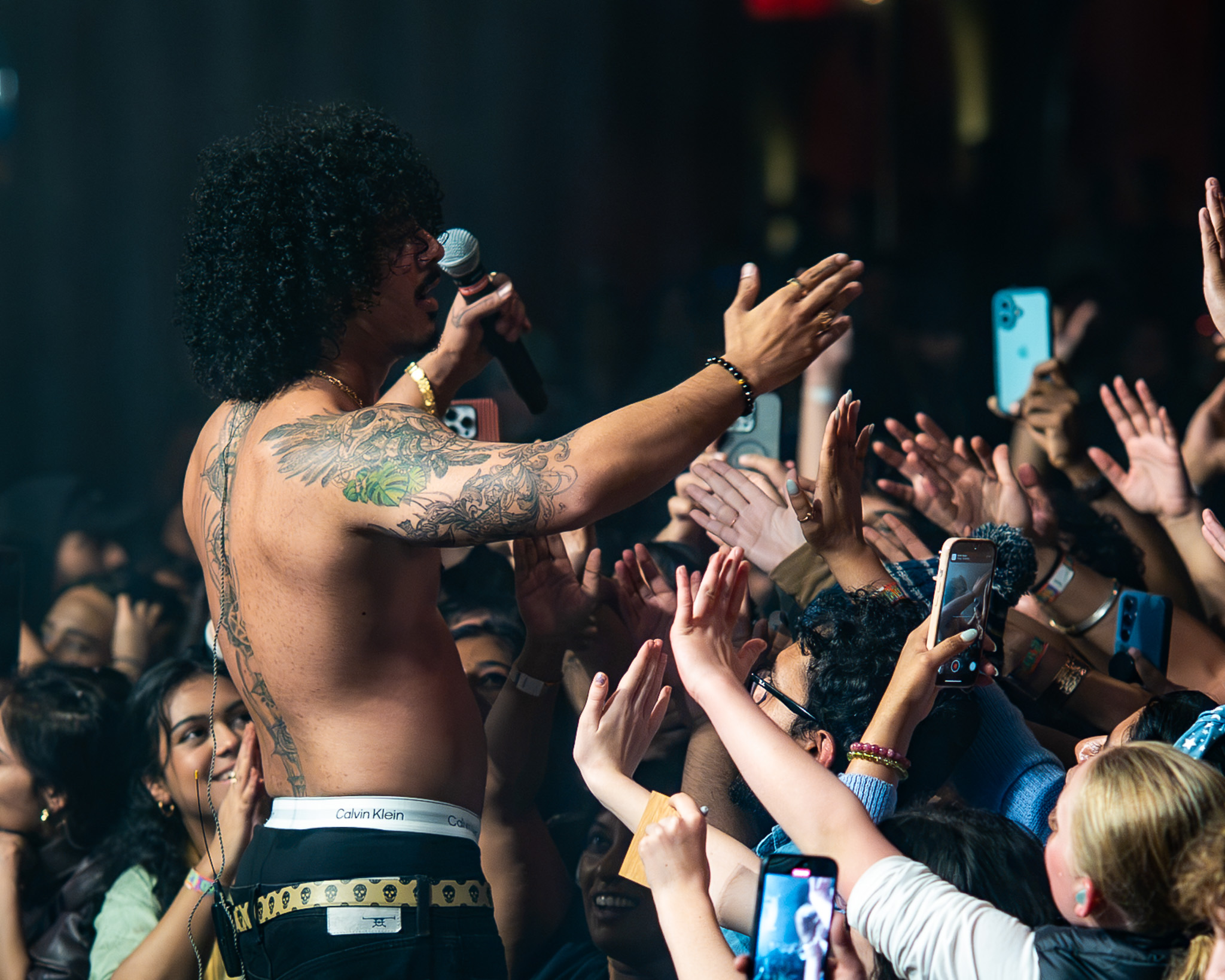 Hanumankind reaches toward a wall of hands and phones in the audience