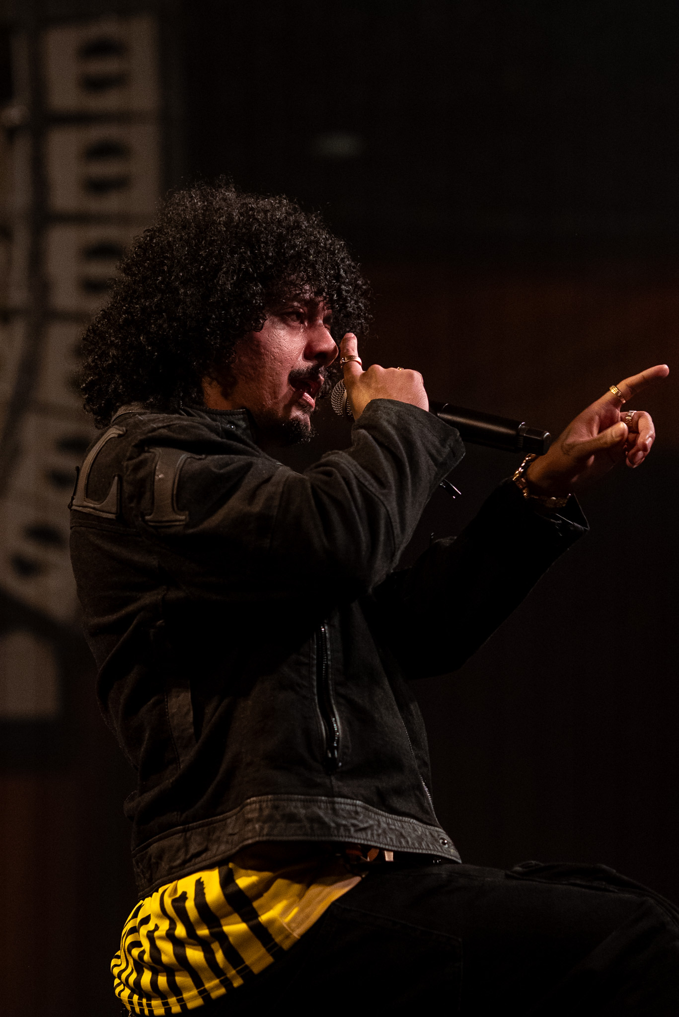Hanumankind points into the room while performing in a black jacket