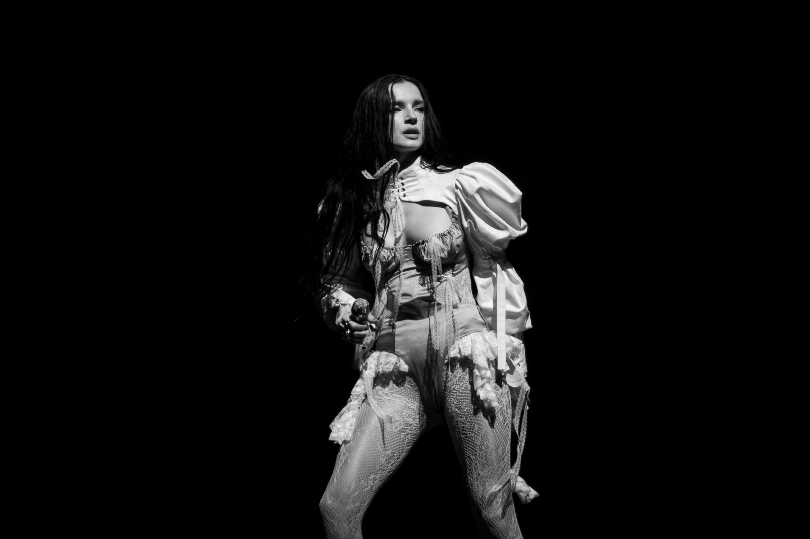Poppy stands in a hard spotlight in a black-and-white photograph