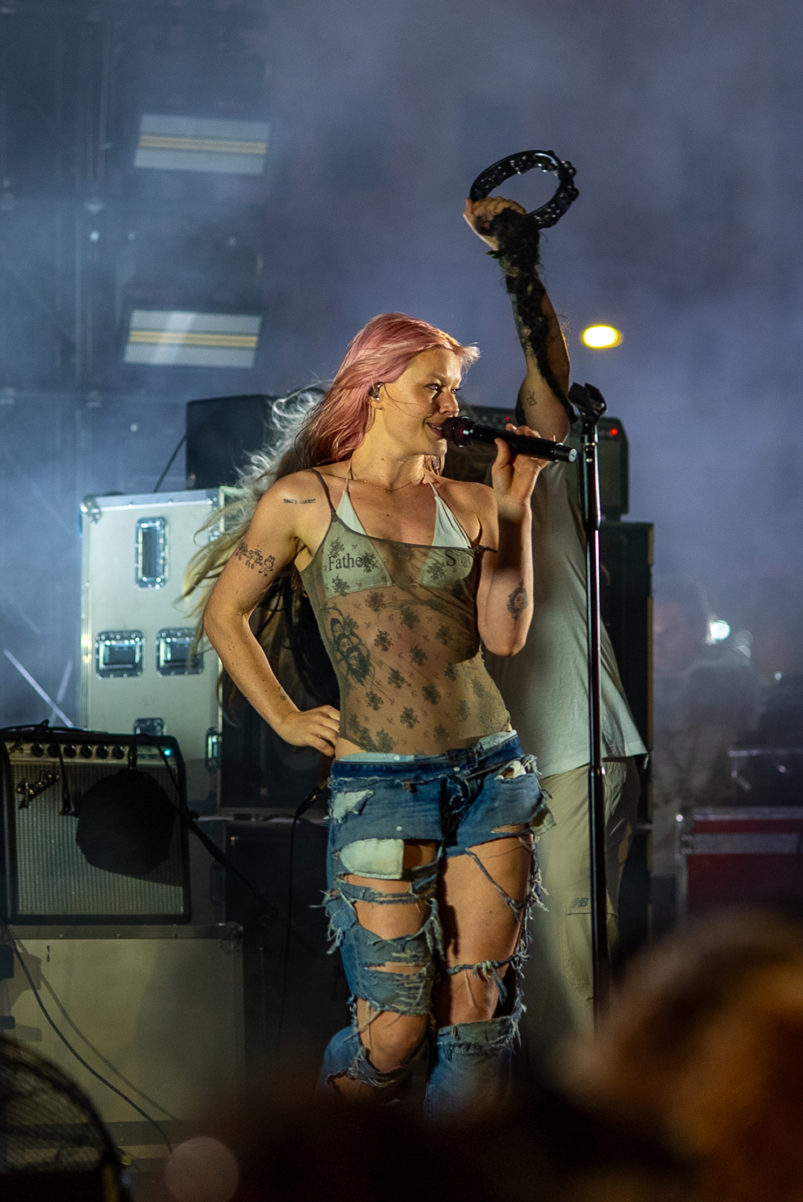Rhian Teasdale singing while a bandmate holds a tambourine overhead